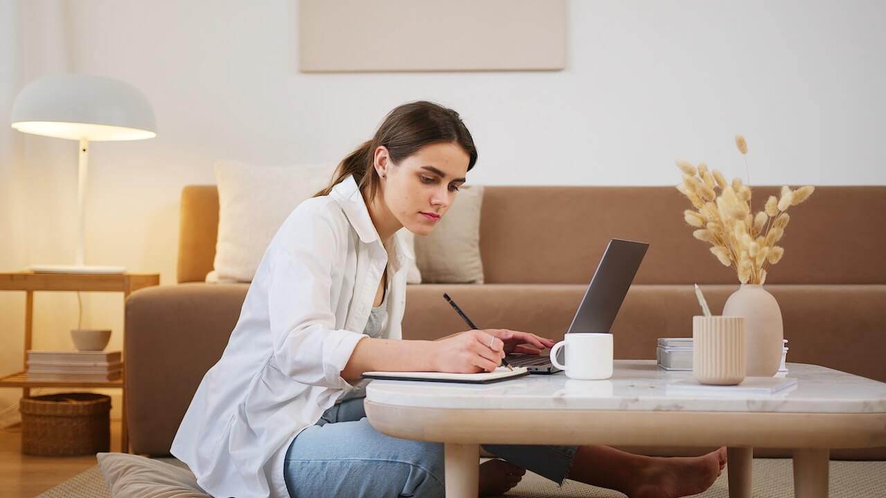 Young woman in front of laptop taking notes